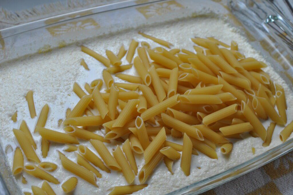 pouring penne pasta into sauce 
