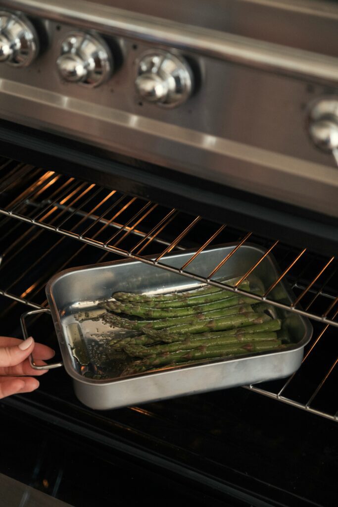putting a trey of asparagus and roasting asparagus in the oven 